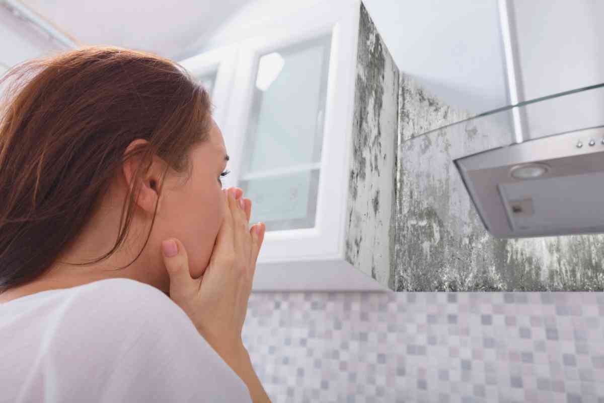 donna preoccupata guarda muffa in cucina
