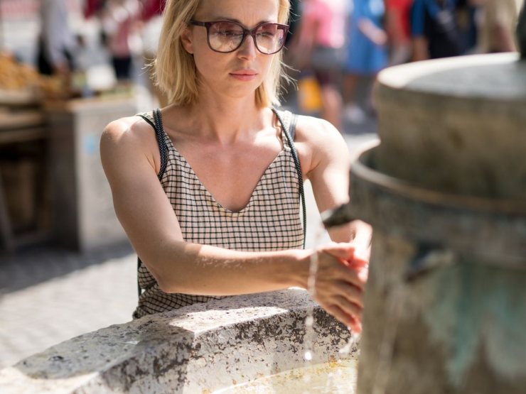 Donna che prende acqua dalle fontanelle