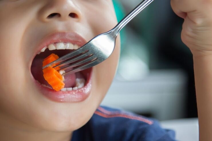 Bambino mangia carota con forchetta