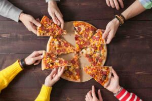 mani che prendono fette di pizza