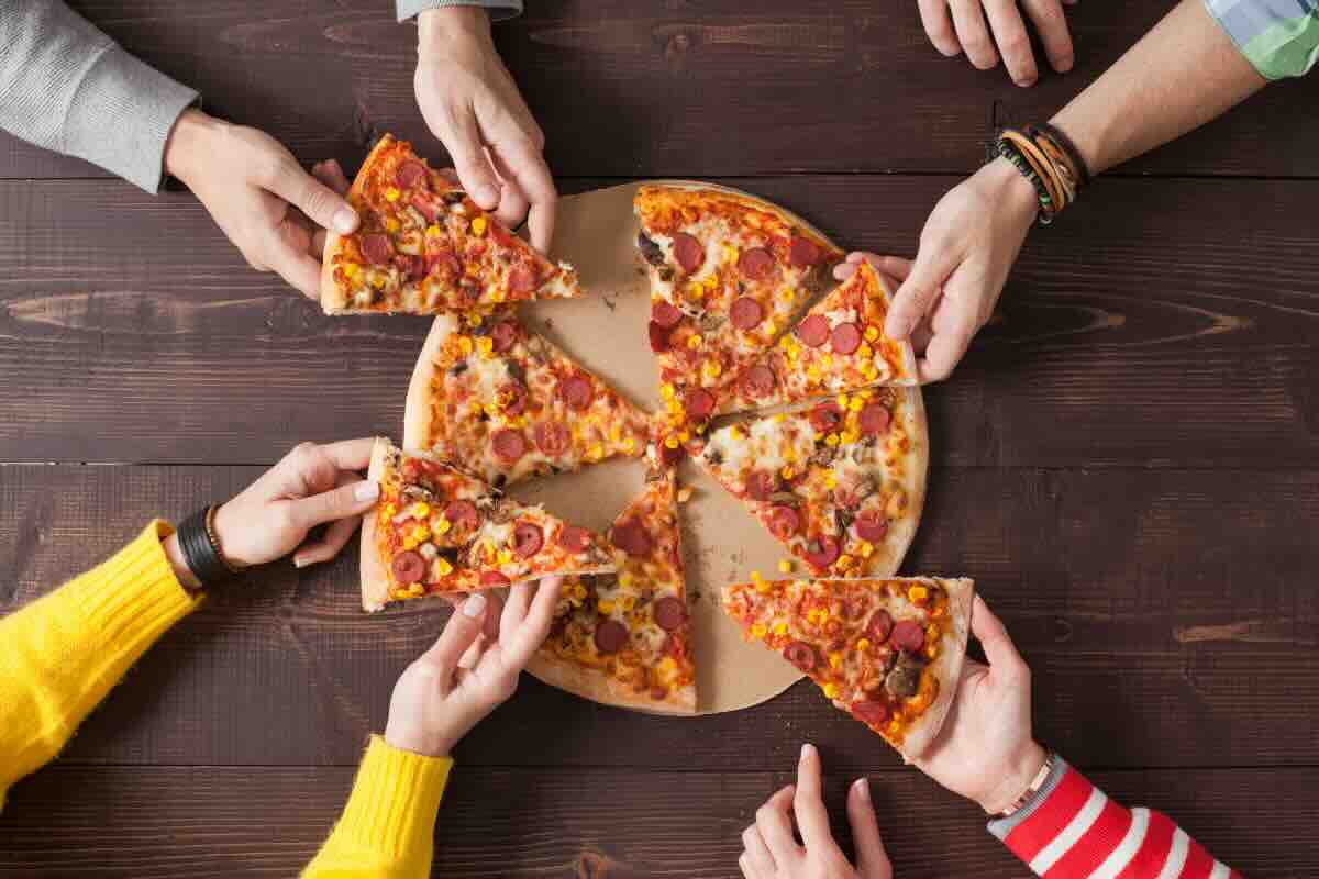 mani che prendono fette di pizza