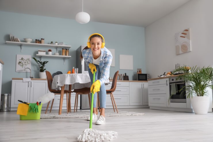 donna felice che ascolta musica e lava pavimenti