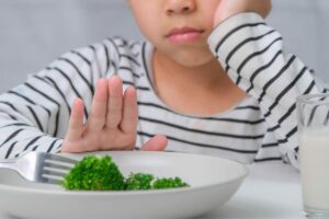 Bambino scontroso mano davanti al piatto con verdure