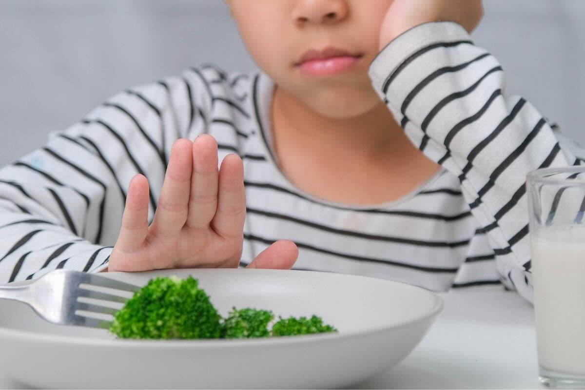 Bambino scontroso mano davanti al piatto con verdure