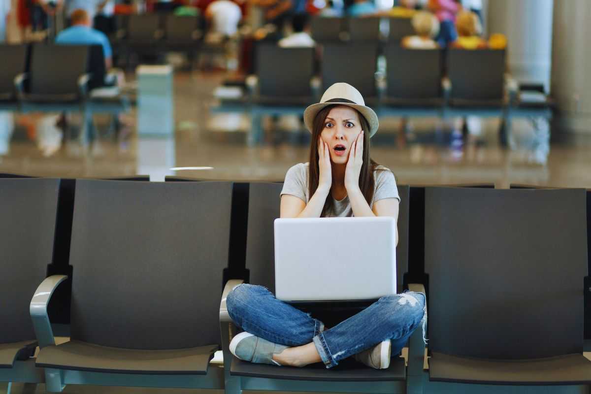 Donna seduta in aeroporto con espressione stupita