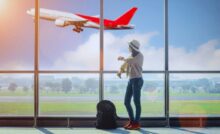 Donna in aeroporto che controlla orario e vede aereo in partenza