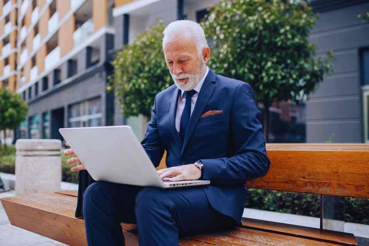Uomo anziano in giacca e cravatta che lavora al PC