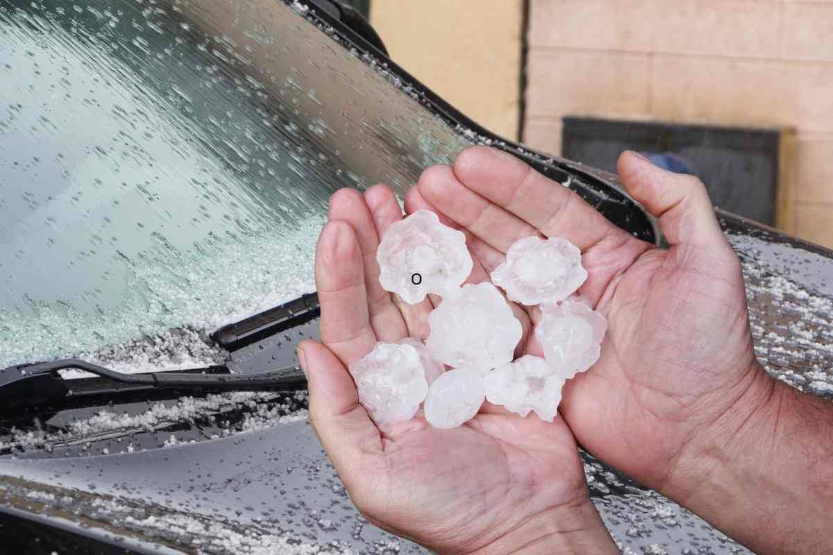 Grandine in mano e auto