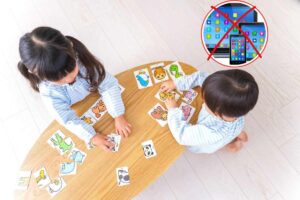 bambini sul tavolino con carte e x su smartphone