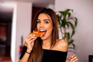 Ragazza felice mangia pezzo di pizza